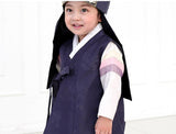 Young boy wearing a navy korean hanbok with hat and smiling