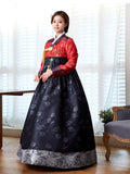 Woman wearing custom mother of the bride hanbok with red top and navy skirt