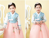 Young girl posing and wearing a girls korean hanbok with blue floral top and pink skirt