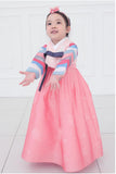 Young girl holding arms out and wearing a girls korean hanbok with pink top and skirt