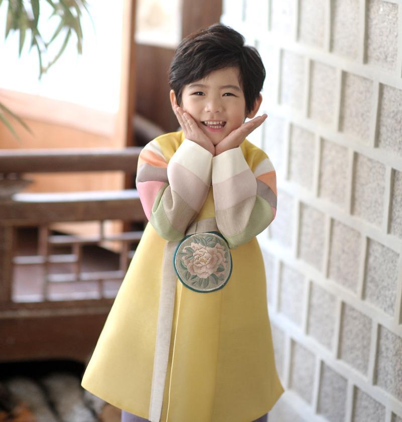 Young boy wearing a yellow and purple korean hanbok with cute smile