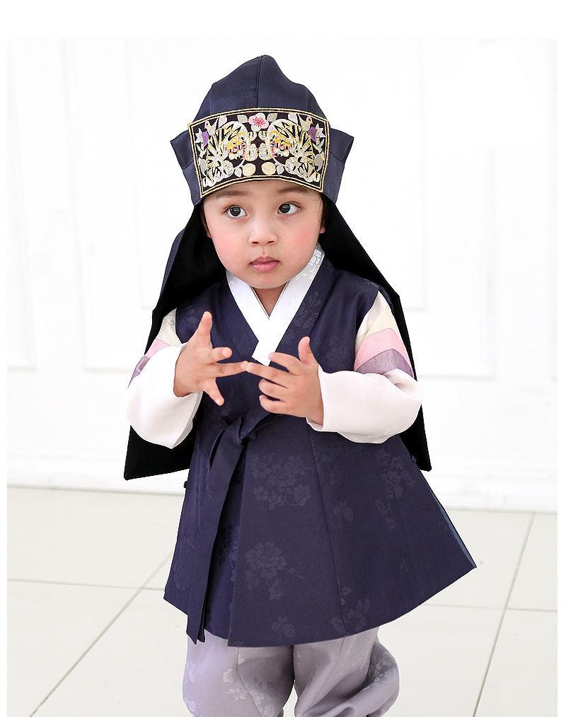 Young boy wearing a navy korean hanbok and touching fingers