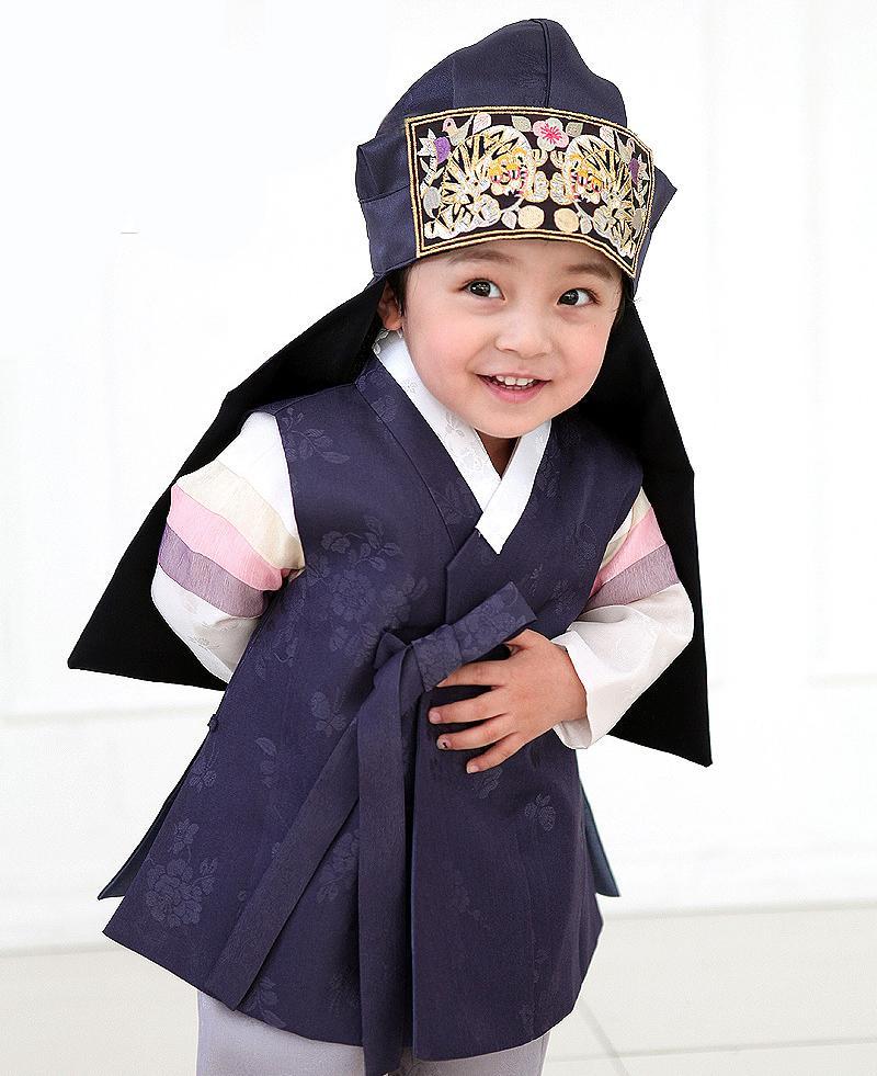 Young boy wearing a navy korean hanbok and bowing