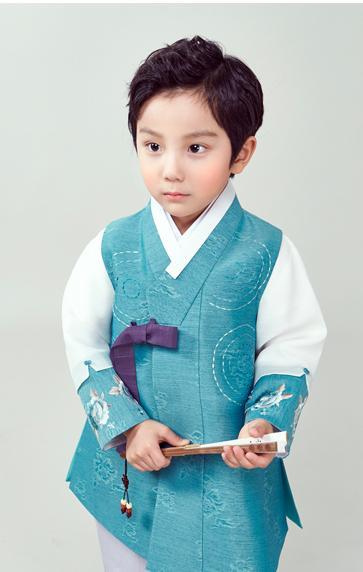 Young boy wearing a sky blue hanbok and holding a fan with two hands