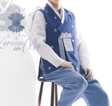Man wearing custom grooms hanbok blue satin top and blue pants while sitting on chair