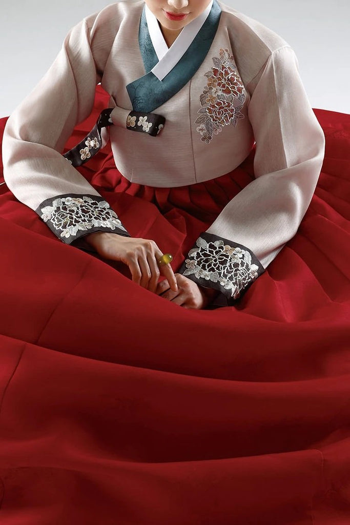 Woman wearing custom mother of the bride hanbok with red top and navy skirt sitting down