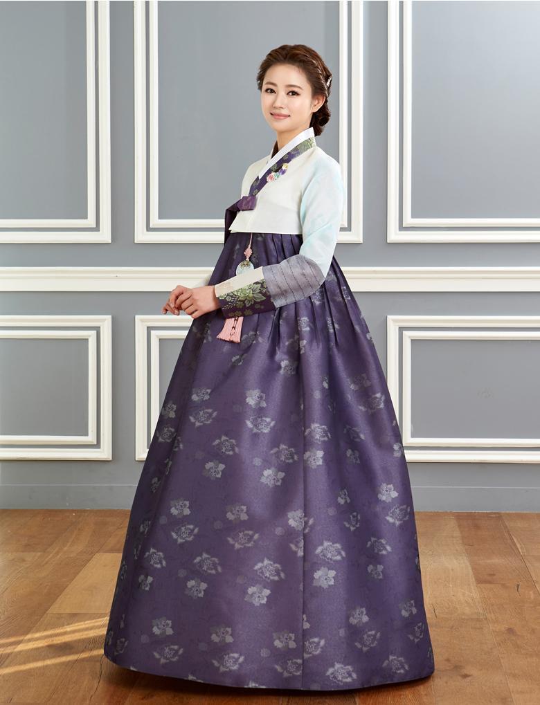 Woman wearing custom mother of the bride hanbok with white top and purple skirt and smiling