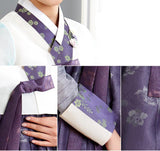 Woman wearing custom mother of the bride hanbok with white top and purple skirt closeup