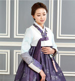 Woman wearing custom mother of the bride hanbok with white top and purple skirt