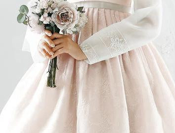 Closeup of womans hands as she wears a custom womens bridal hanbok in lace and pastel pink style