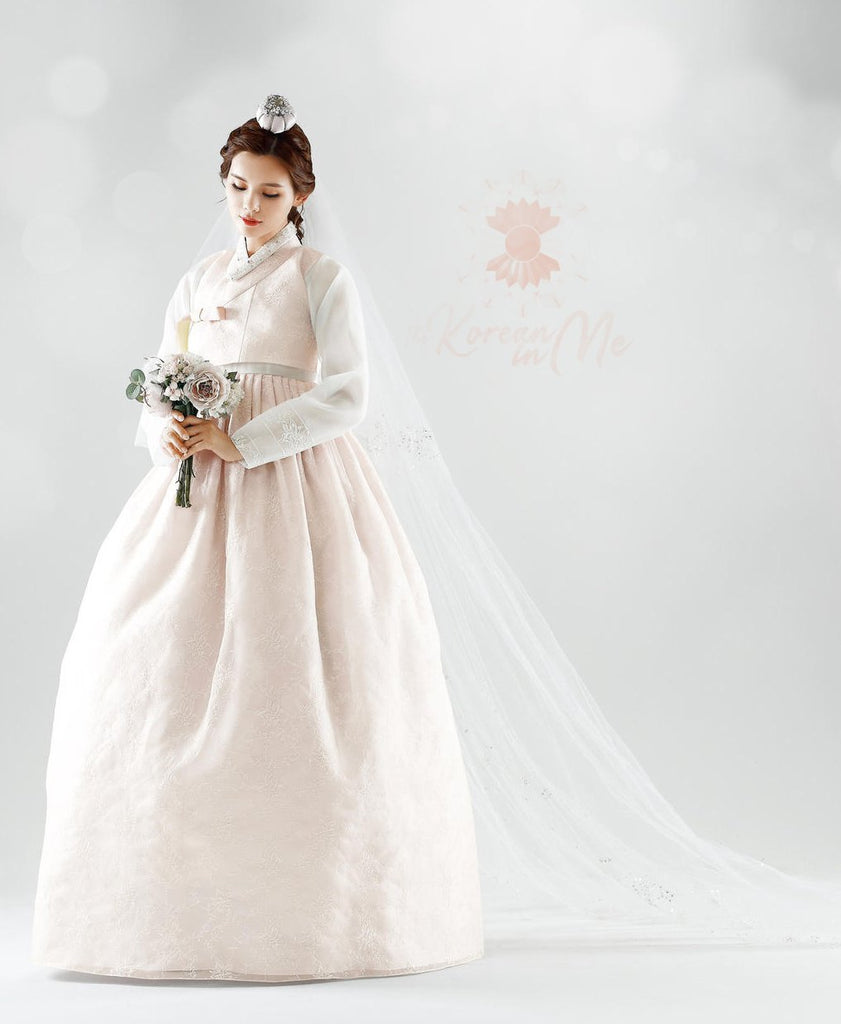 Woman holding a bouquet and wearing a custom womens bridal hanbok in lace and pastel pink style