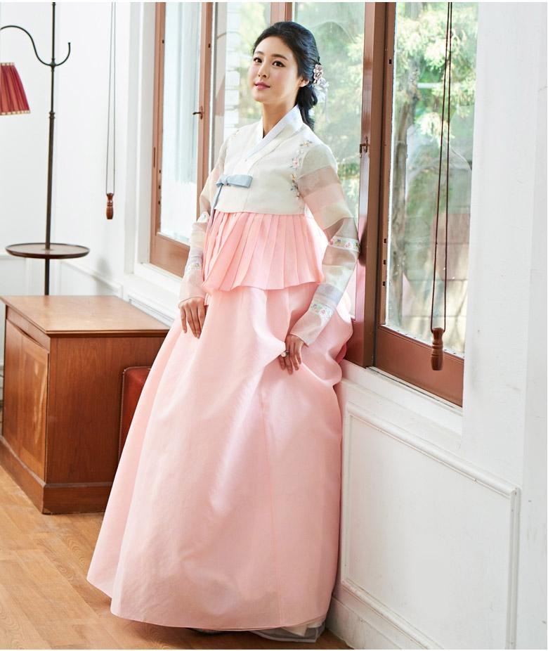 Woman standing by window and wearing a custom womens bridal hanbok in pink