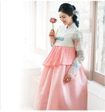 Woman holding a flower and wearing a custom womens bridal hanbok in pink