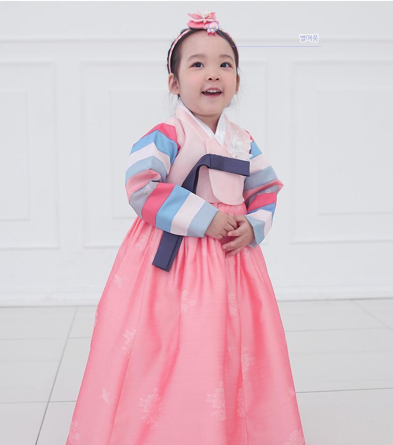 Young girl clasping hands and wearing a girls korean hanbok with pink top and skirt