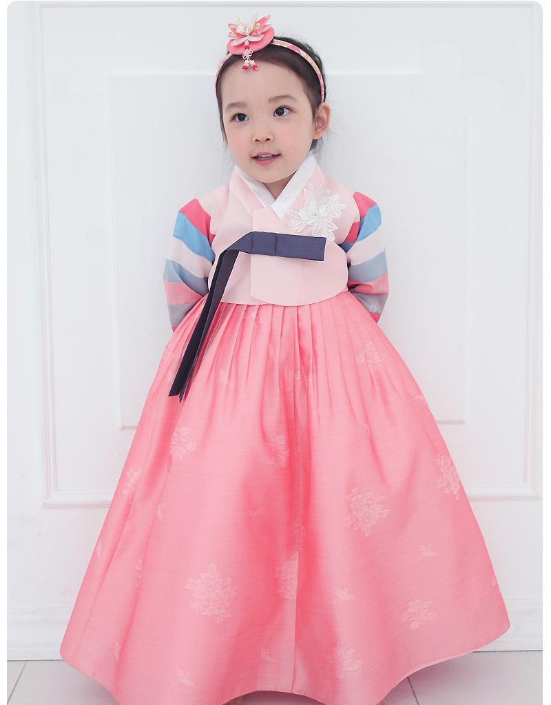 Young girl with hands behind her back and wearing a girls korean hanbok with pink top and skirt