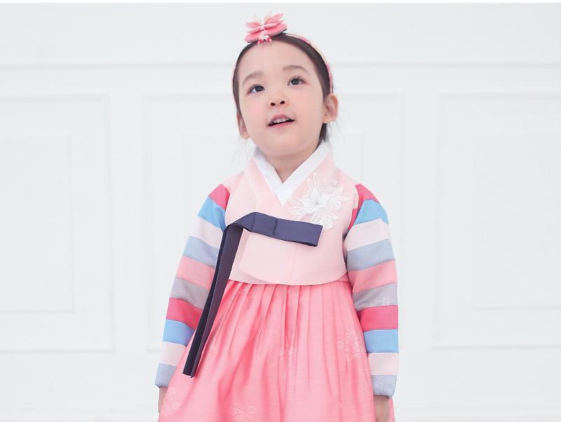 Young girl looking up and wearing a girls korean hanbok with pink top and skirt