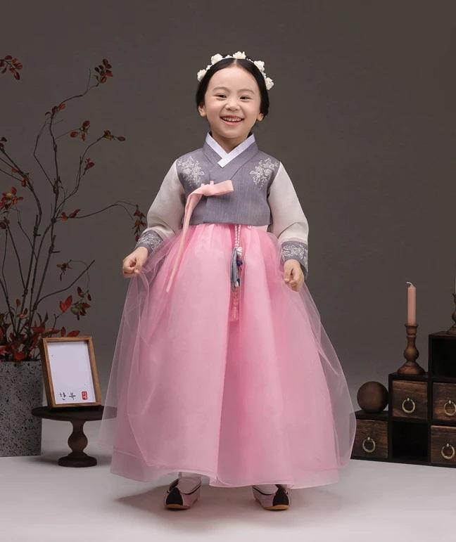 Young girl smiling and wearing a girls korean hanbok with lavender top and pink skirt
