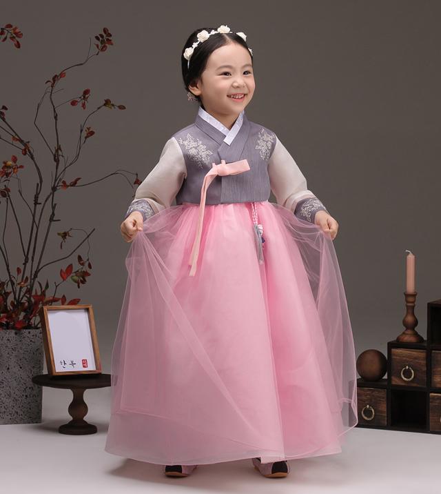 Young girl holding her skirt and wearing a girls korean hanbok with lavender top and pink skirt