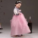 Young girl examining her skirt while wearing a girls korean hanbok with lavender top and pink skirt