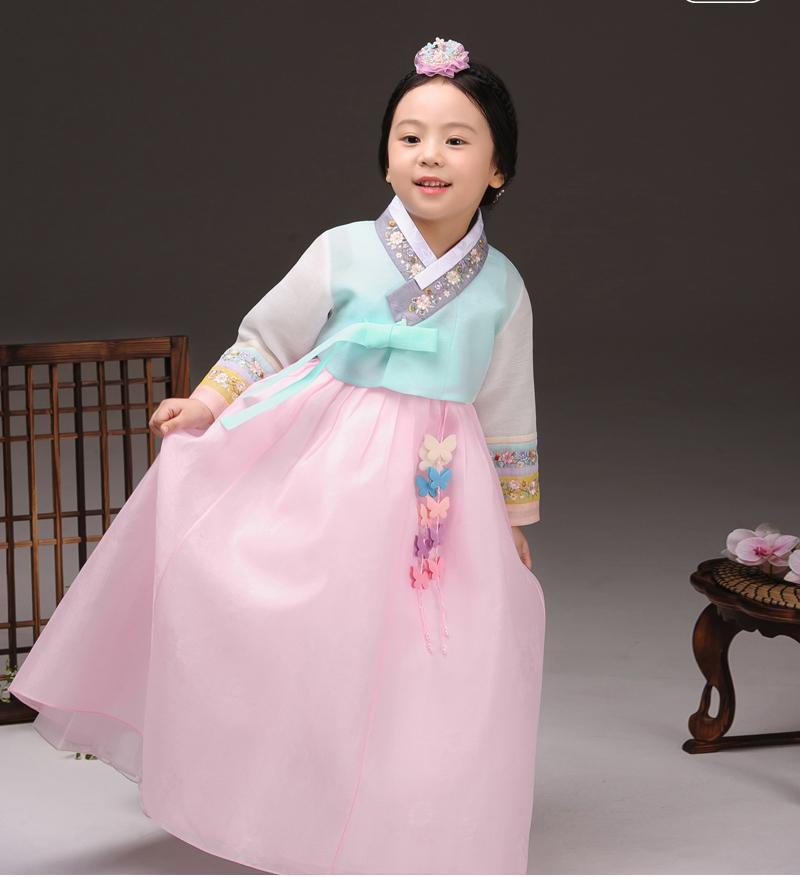 Young girl holding her skirt while wearing a girls korean hanbok with lavender top and pink skirt