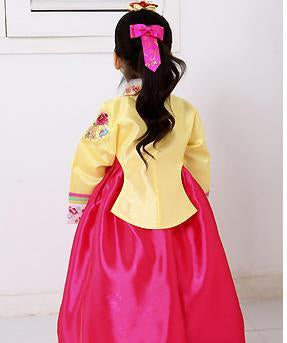 Back view of young girl wearing a girls korean hanbok with yellow top and bright red skirt