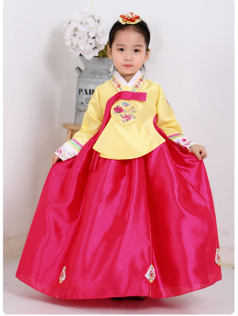 Young girl wearing a girls korean hanbok with yellow top and bright red skirt