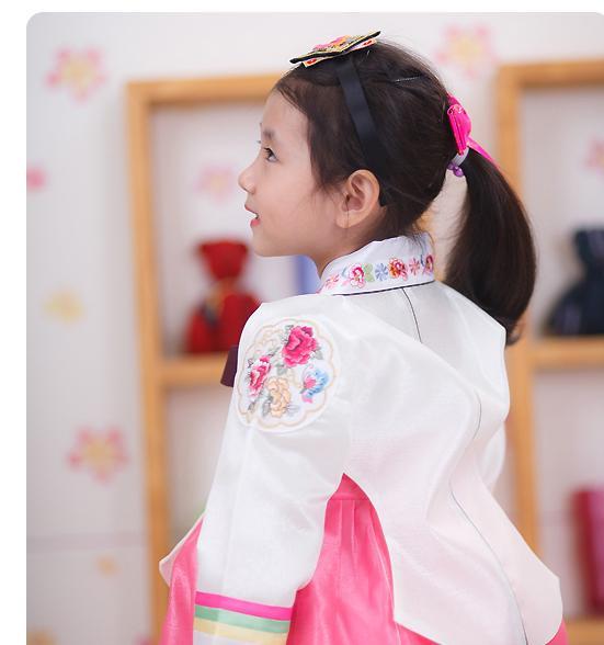Young girl wearing headband and a girls korean hanbok with white top and red skirt